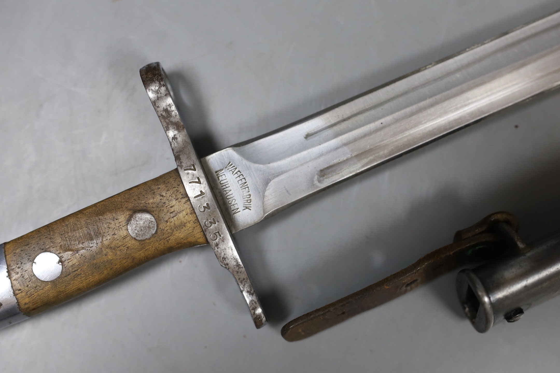 A Swiss bayonette, the blade marked WAFFENFABRIK NEUHAUSEN, hilt serial number 771335, with sheath